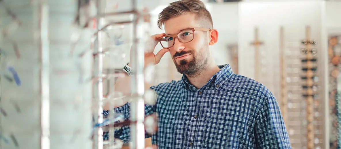 man trying on glasses and looking into a mirror