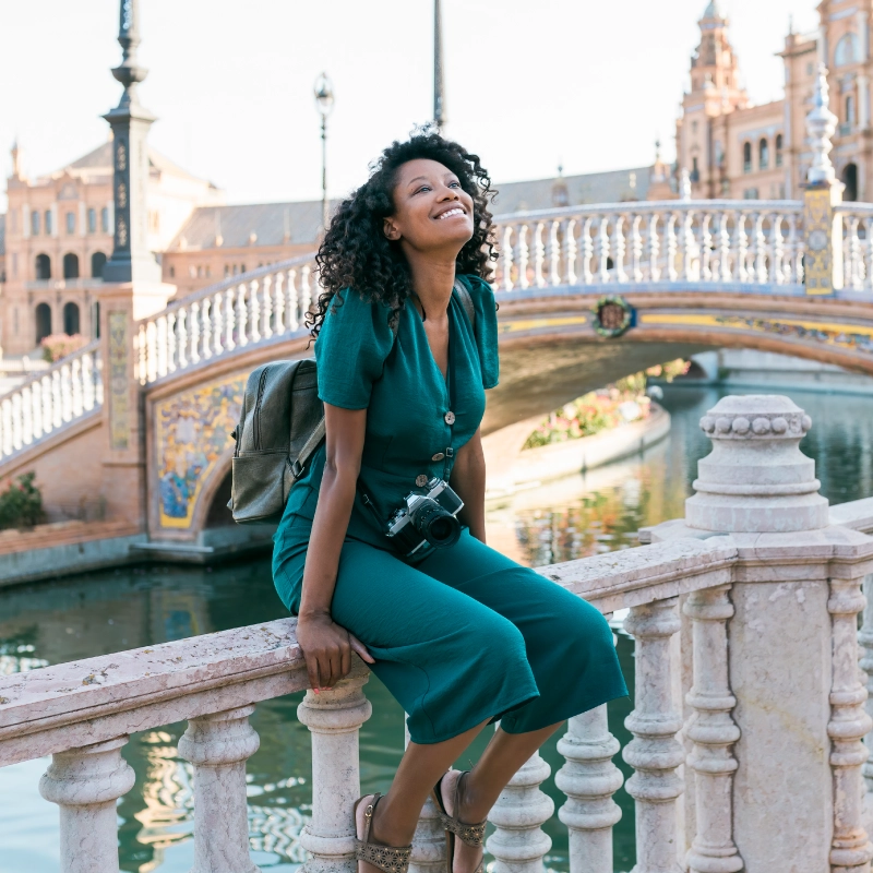 happy-afro-woman-sitting-on-railing-at-plaza-de-royalty